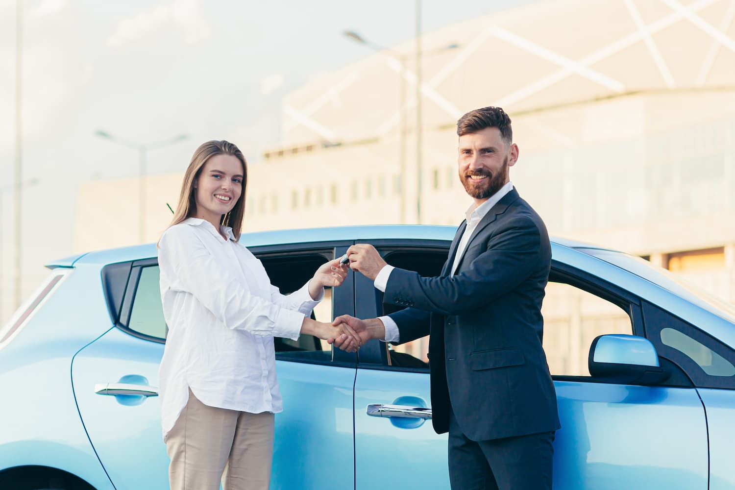 Vendeur de voiture remettant les clés d'une voiture d'occasion à une femme